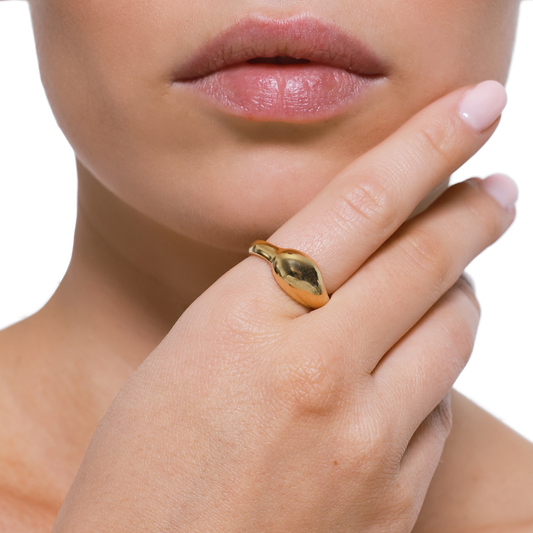 Goldener Blatt-Ring am Finger vor neutralem Hintergrund